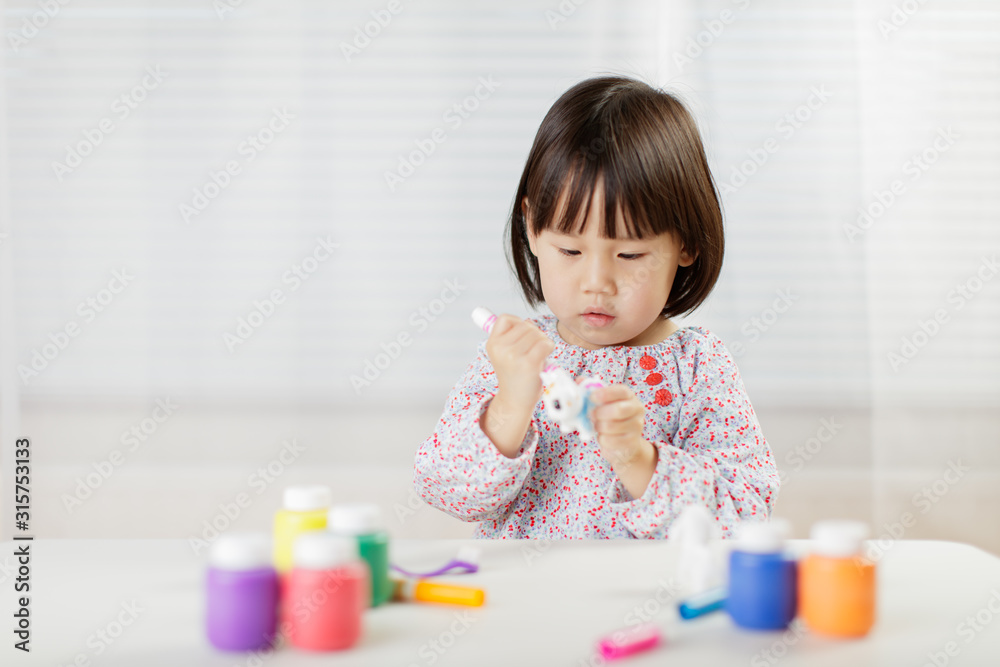 toddler girl watercolor painting on the animal toy at home against white background toddler girl watercolor painting on the animal toy at home against white background