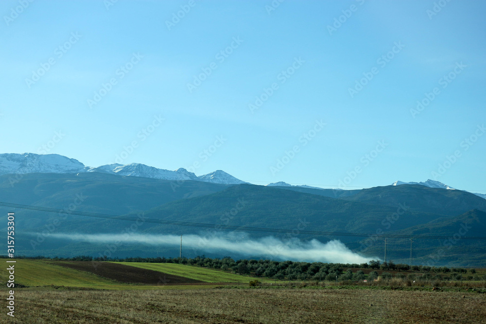 Scenic landscape with sierra nevada mountains and cloud above the fields