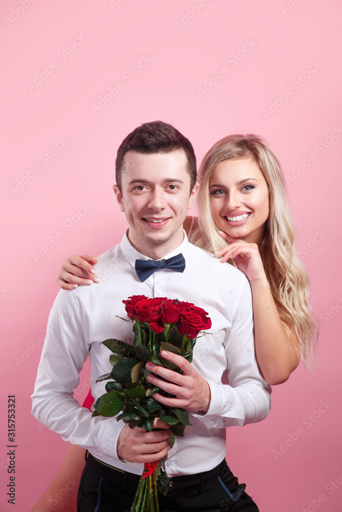 Attractive couple looking at camera and holding flowers Attractive couple looking at camera and holding flowers