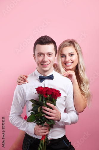 Attractive couple looking at camera and holding flowers
