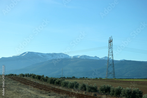 electricity pylon in a field with sierra nevada mountains on the background