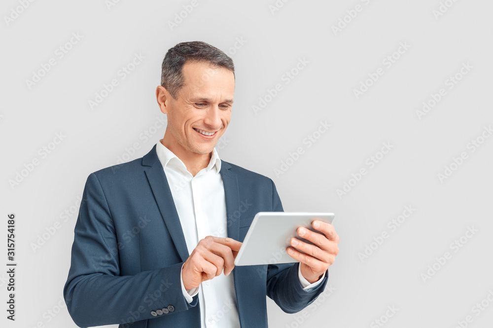 Freestyle. Mature businessman standing isolated on white browsing internet on digital tablet smiling cheerful Freestyle. Mature businessman standing isolated on white browsing internet on digital tablet smiling cheerful