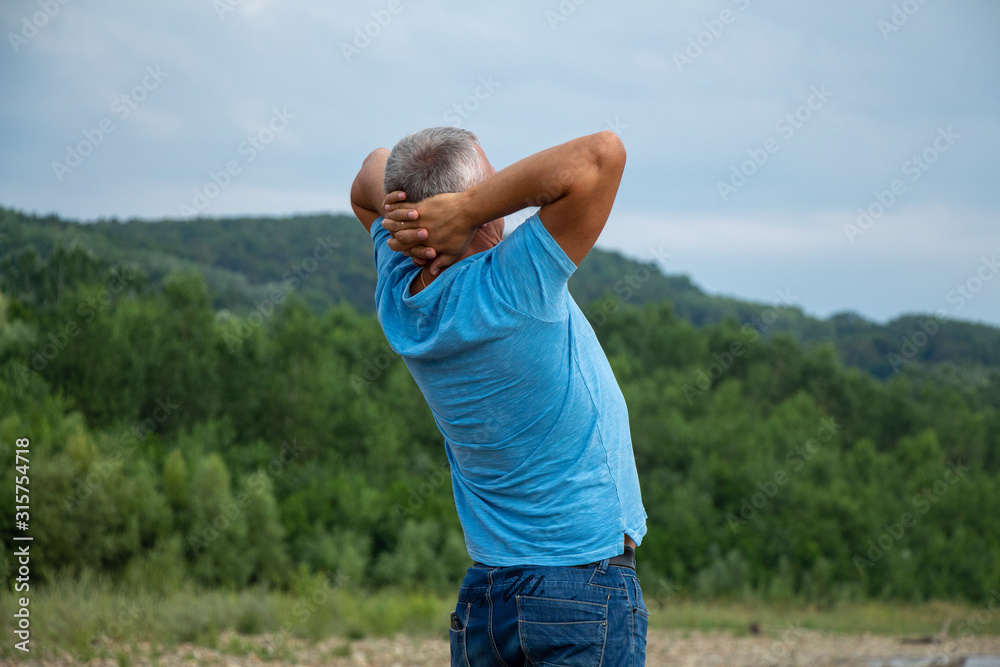 A man stands on the riverbank and looks at the mountains. A man stands on the riverbank and looks at the mountains.