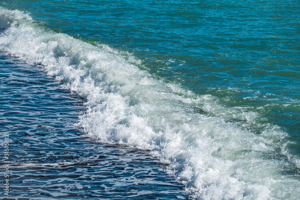 Blue sea wave with foam on the beach