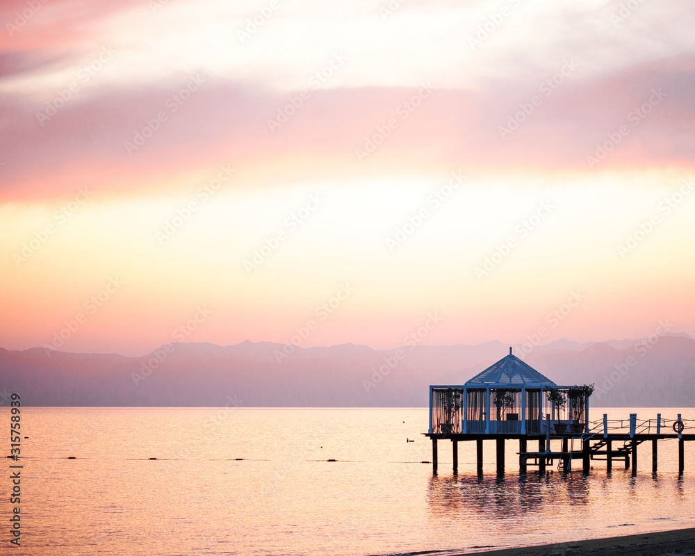 Sunset on the beach, ocean in pink colors. Mountains are visible on the horizon. Turkey.