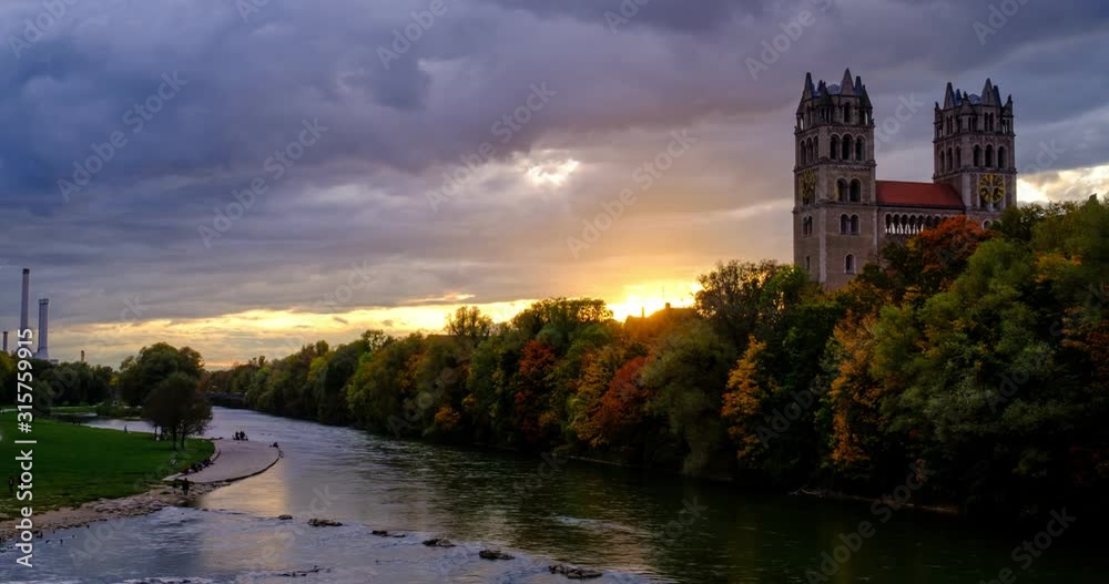 Timelapse of Munich at dramatic sunset: autumn in park of famous tourist landmark Bavarian city. View of Isar river, trees, church. Munchen, Bavaria, Germany. Camera zoom out Timelapse of Munich at dramatic sunset: autumn in park of famous tourist landmark Bavarian city. View of Isar river, trees, church. Munchen, Bavaria, Germany. Camera zoom out