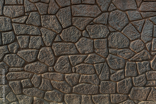 Dark assembled stone wall backdrop. Mosaic pattern of random stones 