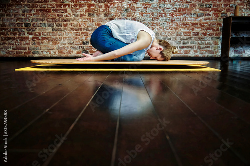 Middle aged woman resting on child pose on mat in yin yoga class. Healthy lifestyle concept