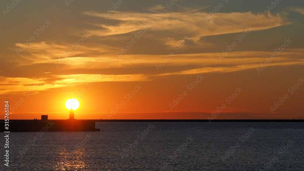 Very beautiful sunset over the pier. Bright orange sun disc.