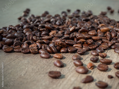 Black coffee in grains on the surface of a wooden table.
