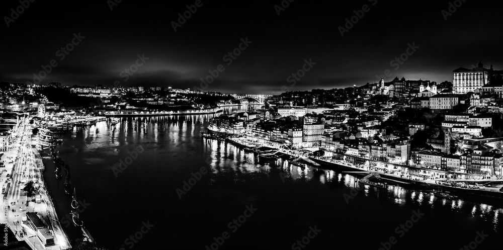 Black and white night cityscape panorama of Porto old town and river Douro banks skyline with water reflections in Porto, Portugal