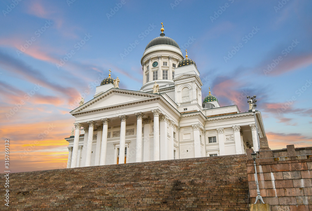 The neoclassical Helsinki Cathedral and the steps leading up to it from the Senate Square under a colorful sunset sky in Helsinki Finland.