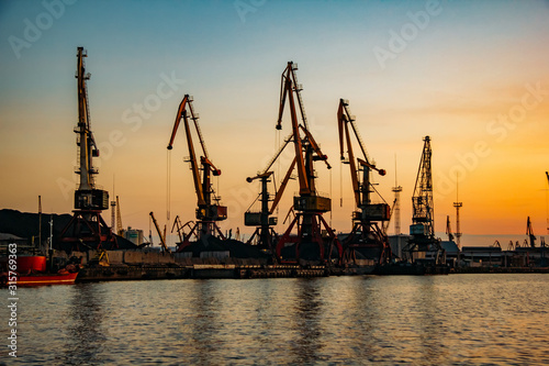Harbor cargo cranes on sunset sky background