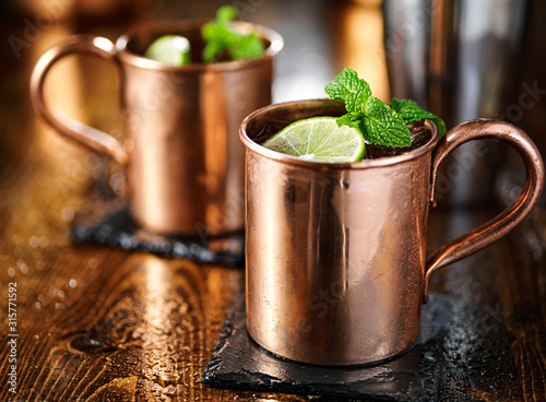 Photography two moscow mules in copper cup wih lime and mint garnish