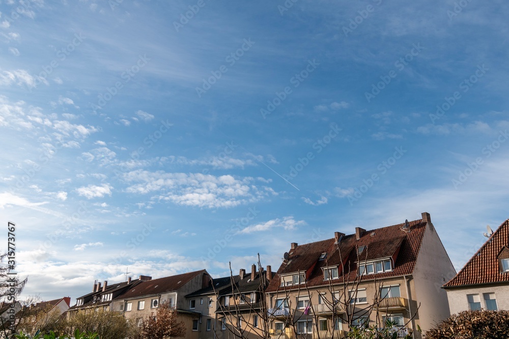 blue cloudy sky over three storey houses blue cloudy sky over three storey houses