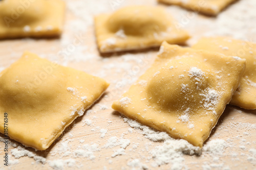 Raw ravioli on wooden board, closeup view. Italian pasta