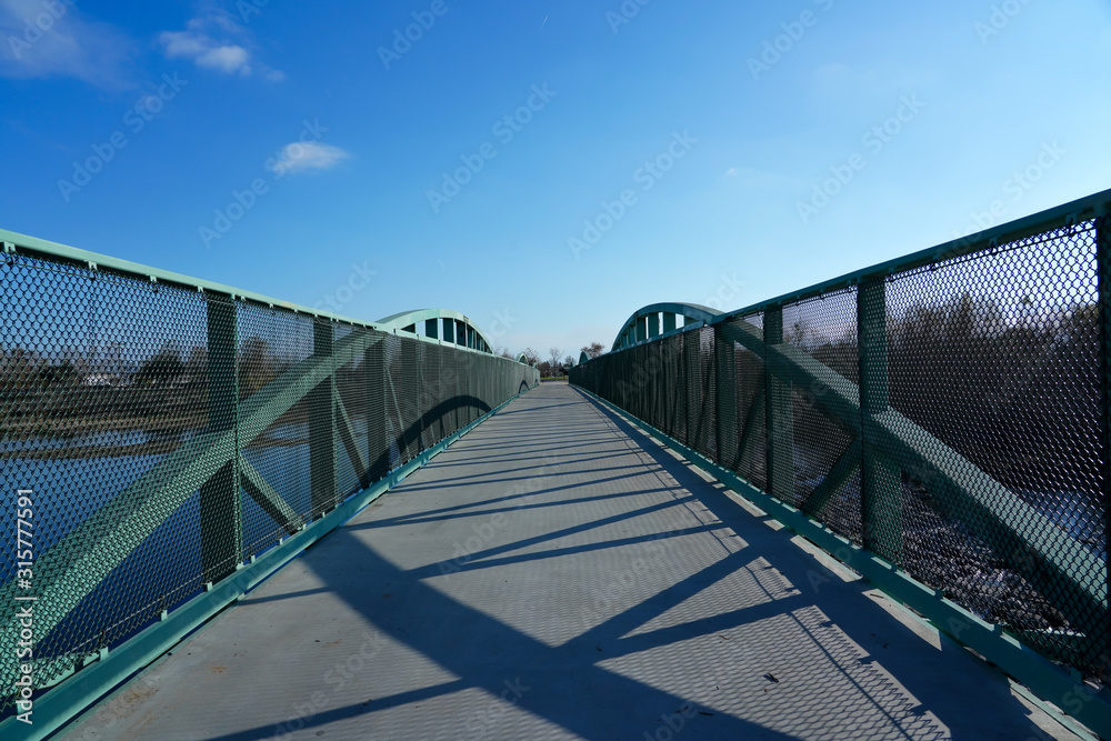 Walking bridge over river to other side, outdoor activities.