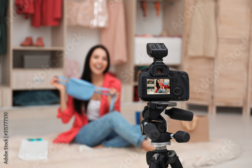 Fashion blogger recording new video in room, focus on camera