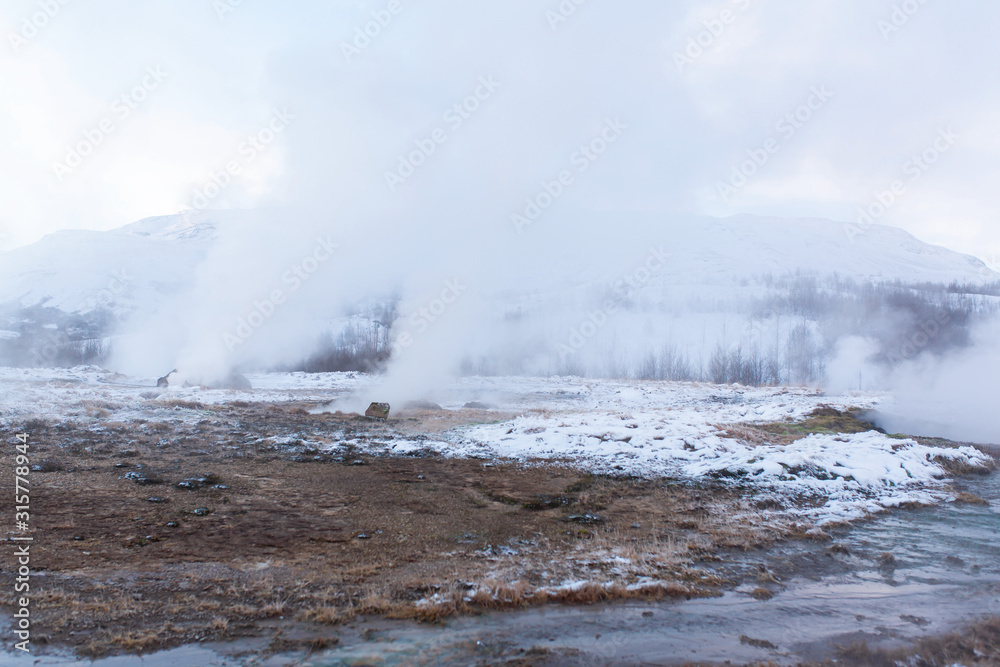 An erupting soaring geyser in the Valley of Geysers. Magnificent Iceland in the winter. An erupting soaring geyser in the Valley of Geysers. Magnificent Iceland in the winter.
