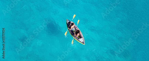 Fotografia, Obraz Aerial drone ultra wide photo of 2 unidentified fit women canoeing in tropical C