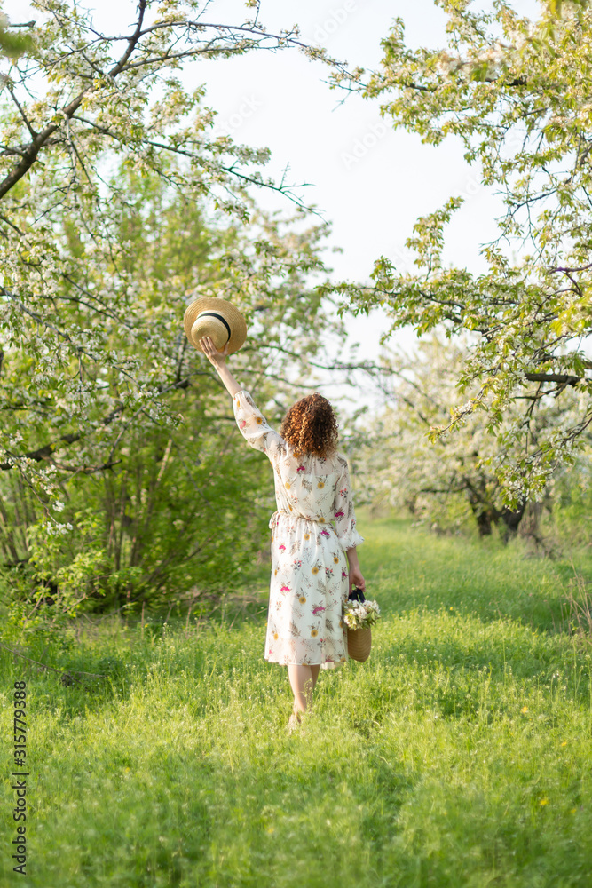 A gorgeous girl walks in a flowering spring garden. The concept of unity of man with nature A gorgeous girl walks in a flowering spring garden. The concept of unity of man with nature