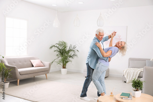 Happy mature couple dancing together in living room © New Africa