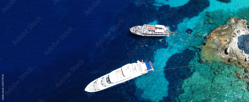 Aerial drone ultra wide photo of sailing yacht docked in paradise turquoise sea exotic island destination Aerial drone ultra wide photo of sailing yacht docked in paradise turquoise sea exotic island destination