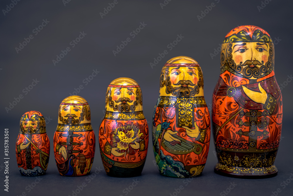 Traditional Russian matryoshka dolls lined up against gray background, doll within a doll, object within an object, metaphor for shell companies, Russian nesting doll 7 Traditional Russian matryoshka dolls lined up against gray background, doll within a doll, object within an object, metaphor for shell companies, Russian nesting doll 7