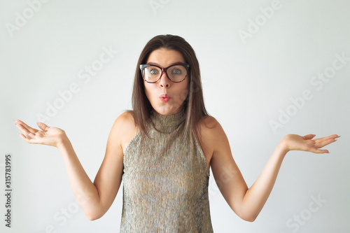 Young girl with long brown hair holds imaginary copyspace on her palm laughing. She is dressed up in white t-shirt.
