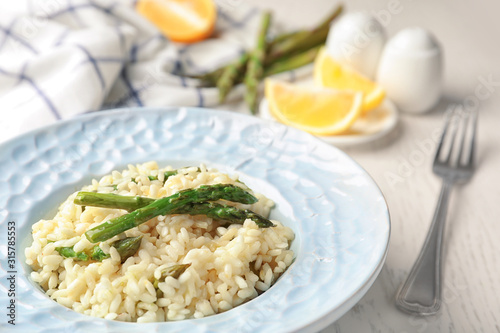 Delicious risotto with asparagus on white wooden table, closeup