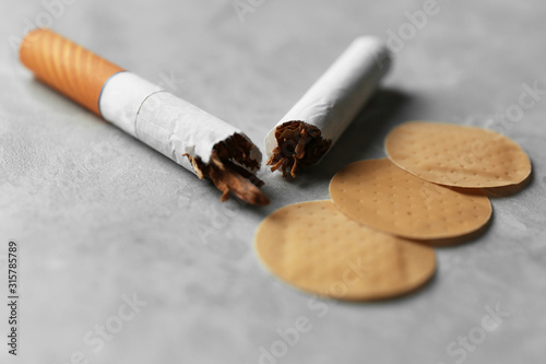 Nicotine patches and broken cigarettes on grey table, closeup photo