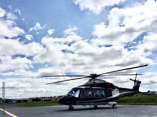 Large executive helicopter parked in airport waiting for businessman in sunny day