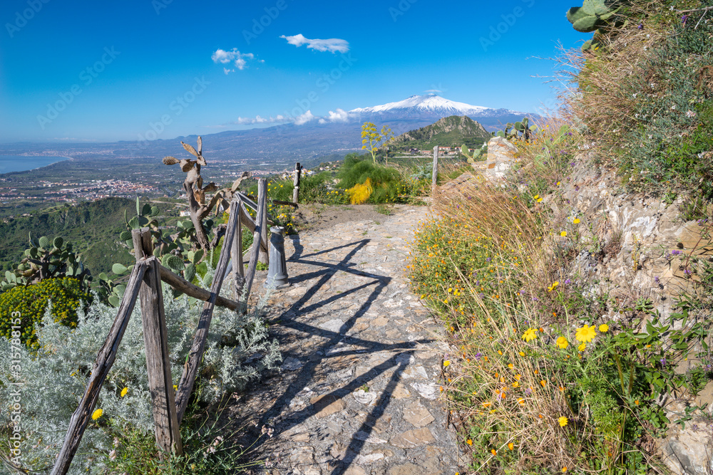Taormina - The path among the spring mediterranean flowers and the Mt. Etna volcano.