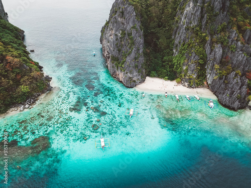 Aerial shot of beautiful crystal clear ocean waters surrounded by cliffs