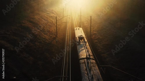 Suburban train goes to sunset through autumn forest. photo