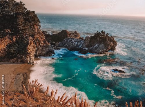 Small gulf of deep blue water, waves crashing into cliffside photo