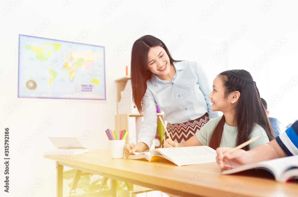 asian students studying and do work with teacher in classroom, asian teacher teaching and explaining about how to do homework, happiness elementary school asian students studying and do work with teacher in classroom, asian teacher teaching and explaining about how to do homework, happiness elementary school