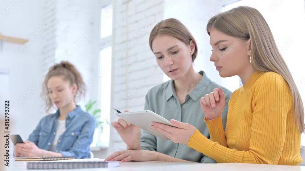 Young Female Designers Discussing and working on Tablet Young Female Designers Discussing and working on Tablet