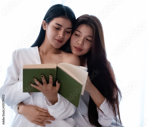 Two beautiful women reading book,doing activity together,closed relationship,portrait of model posing,blurry light around