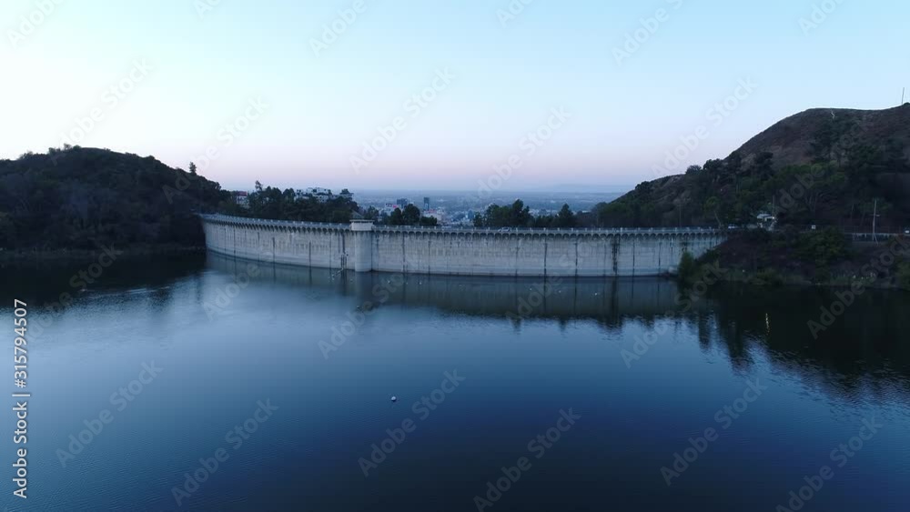 Aerial over blue water of Hollywood reservoir lake towards dam wall, Los Angeles city background Aerial over blue water of Hollywood reservoir lake towards dam wall, Los Angeles city background