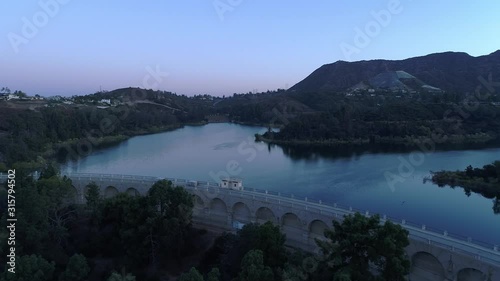 Aerial over the Hollywood Reservoir dam and water in soft blue morning light, Los Angeles