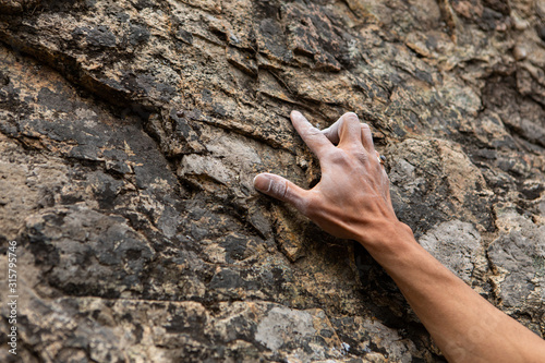 A close up view on the chalked hand of a traditional rock climber ascending a cliff Fototapeta