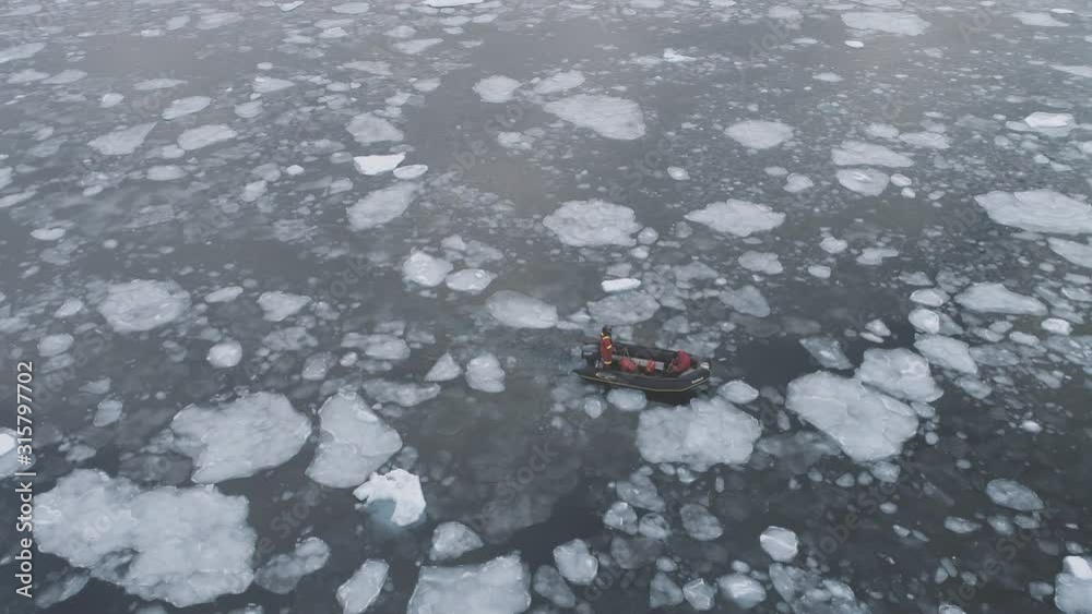 People in rubber inflatable motor boat sail in Antarctic ice. Zodiac in Icebergs, Tracking Aerial Top-Down View. Expedition Transport Exploring Extreme Winter Cold Water. Drone Footage 4K (UHD) People in rubber inflatable motor boat sail in Antarctic ice. Zodiac in Icebergs, Tracking Aerial Top-Down View. Expedition Transport Exploring Extreme Winter Cold Water. Drone Footage 4K (UHD)