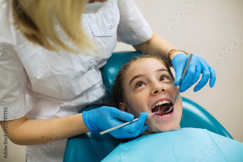 Dentist doing teeth checkup of little girl at medical stomatology clinic.