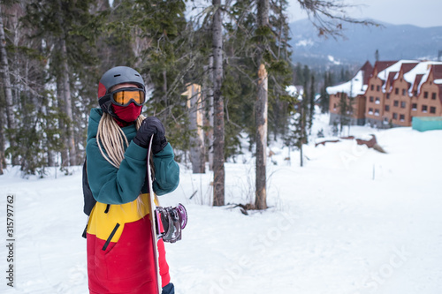 Young woman snowboarder stands with a snowboard.