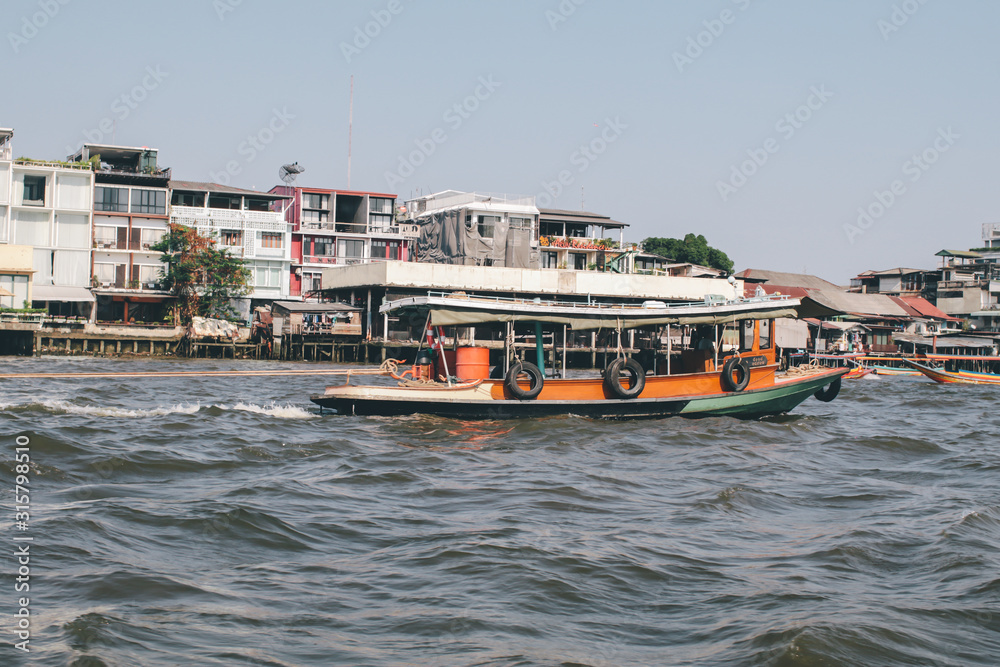 BANGKOK,THAILAND -January 16,2020 Boat in chaopaya river.Passengers on the shuttle boat ,The boat at Chaopaya riverside in Bangkok Thailand,River font and city landscape blue sky horizontal line, ,sel BANGKOK,THAILAND -January 16,2020 Boat in chaopaya river.Passengers on the shuttle boat ,The boat at Chaopaya riverside in Bangkok Thailand,River font and city landscape blue sky horizontal line, ,sel