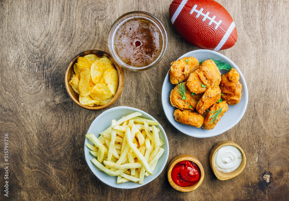 Table fof tasty snacks and beer prepared for watching sports on TV. Wooden background. Top view. Flat lay Table fof tasty snacks and beer prepared for watching sports on TV. Wooden background. Top view. Flat lay