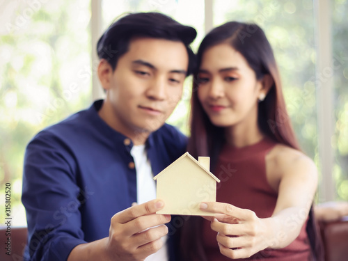 young Asian couple holding model house , selective focus on model house.