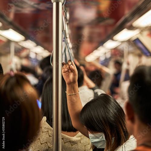Woman in focus in a subway car during rush our.