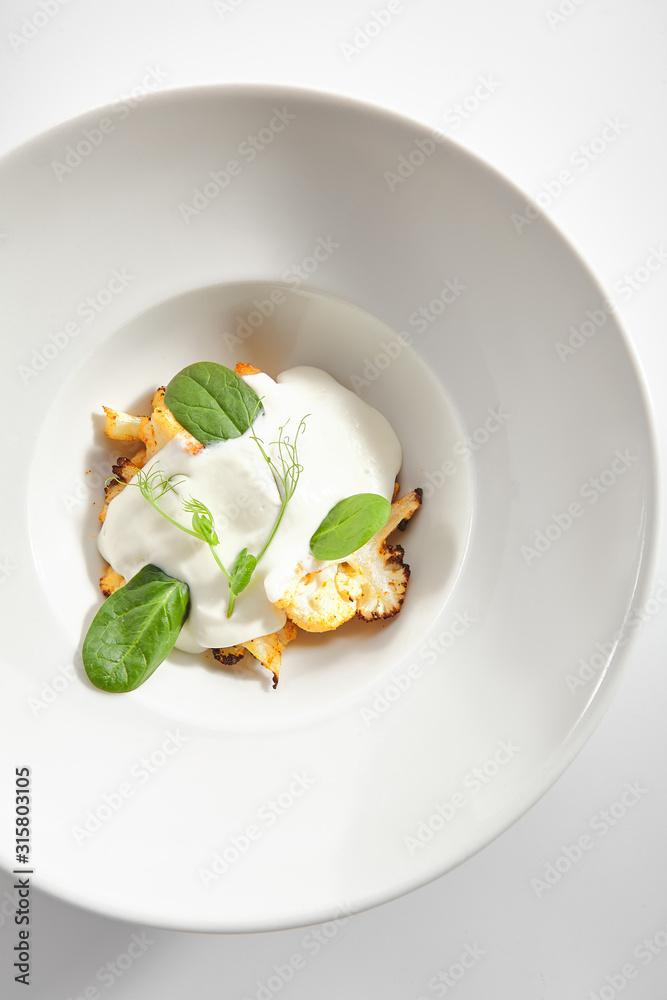 Baked Cauliflower with Cream Sauce and Fresh Greens Isolated Baked Cauliflower with Cream Sauce and Fresh Greens Isolated